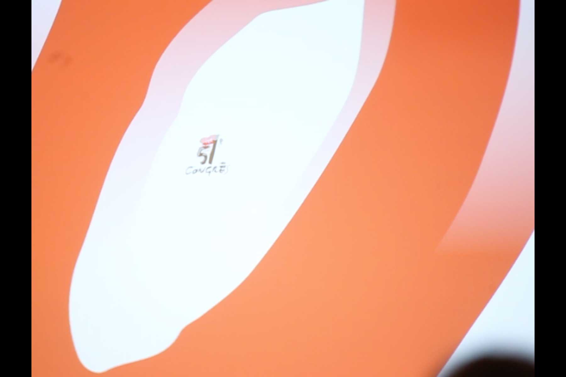 Projektion mit einer Grafik in rot und gelb, die einen Teil des Slogans 