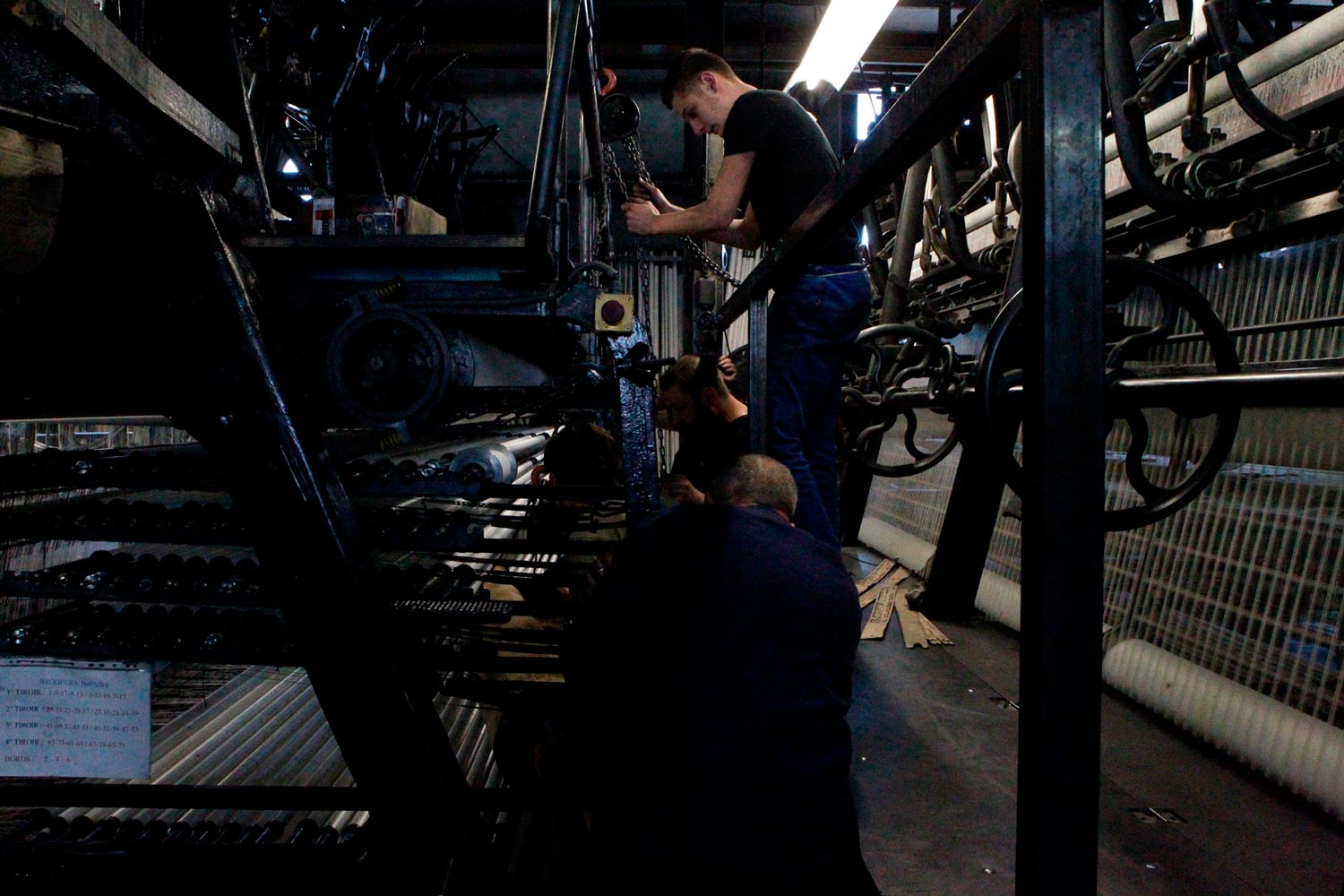 Der junge Arbeiter Matthieu trägt mit anderen Arbeitern eine große Textilspule (Chaine) in die Textilfirma Codentel  Fotografie von Heiko Schäfer