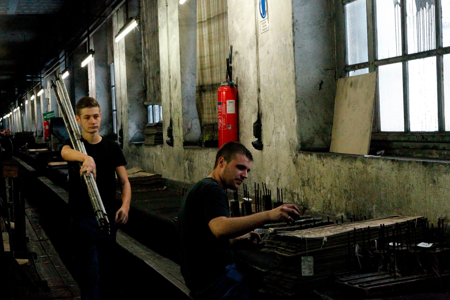 Der junge Textilarbeiter Matthieu trägt Textilspulen in der Textilfirma Codentel  Fotografie von Heiko Schäfer