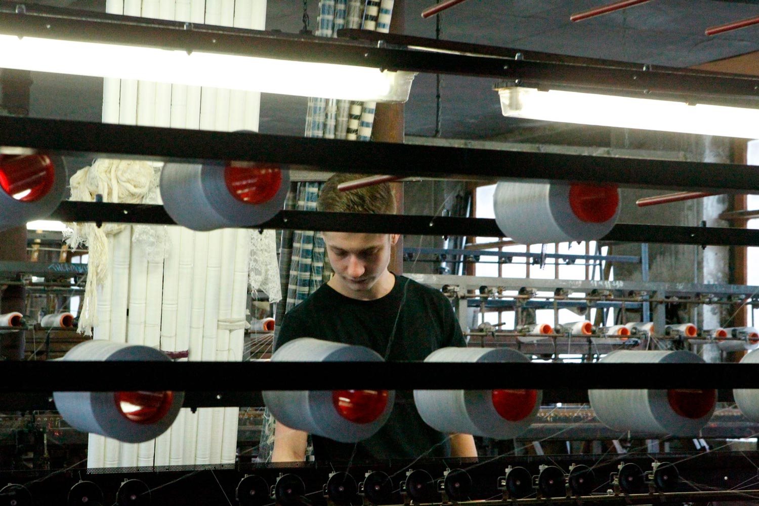 Der junge Arbeiter Matthieu arbeitet an einer Maschine in der Textilfirma Codentel  Fotografie von Heiko Schäfer