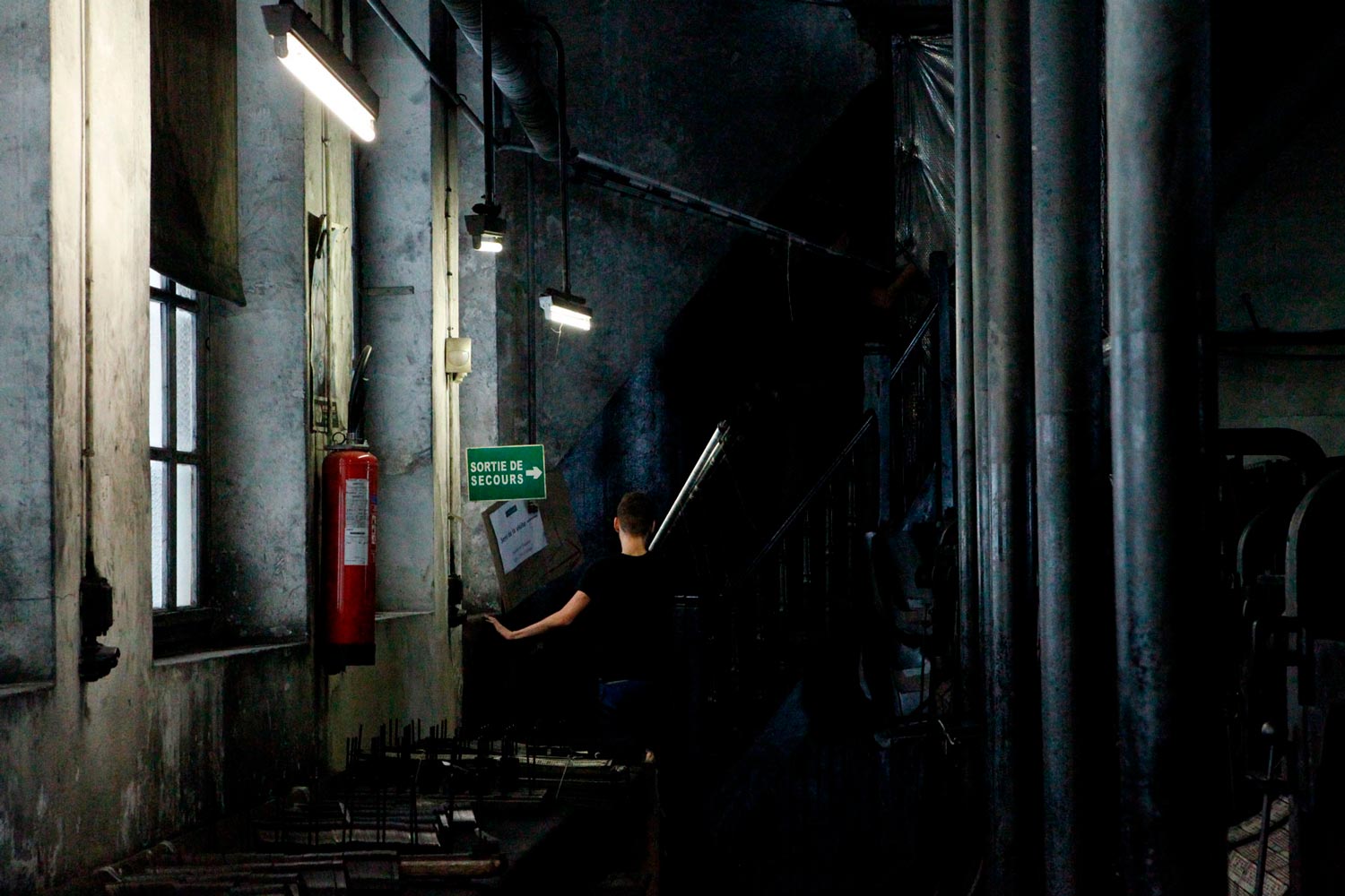 Der junge Textilarbeiter Matthieu trägt Textilspulen in der Textilfirma Codentel  Fotografie von Heiko Schäfer