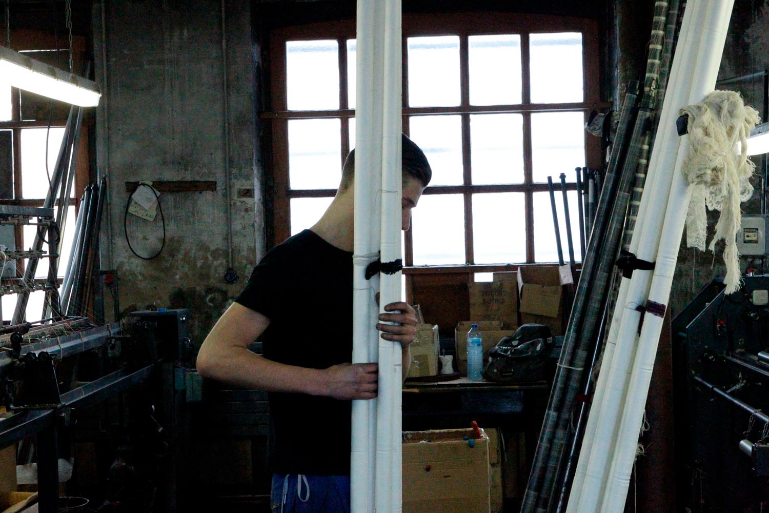 Der junge Textilarbeiter Matthieu trägt Textilspulen in der Textilfirma Codentel  Fotografie von Heiko Schäfer