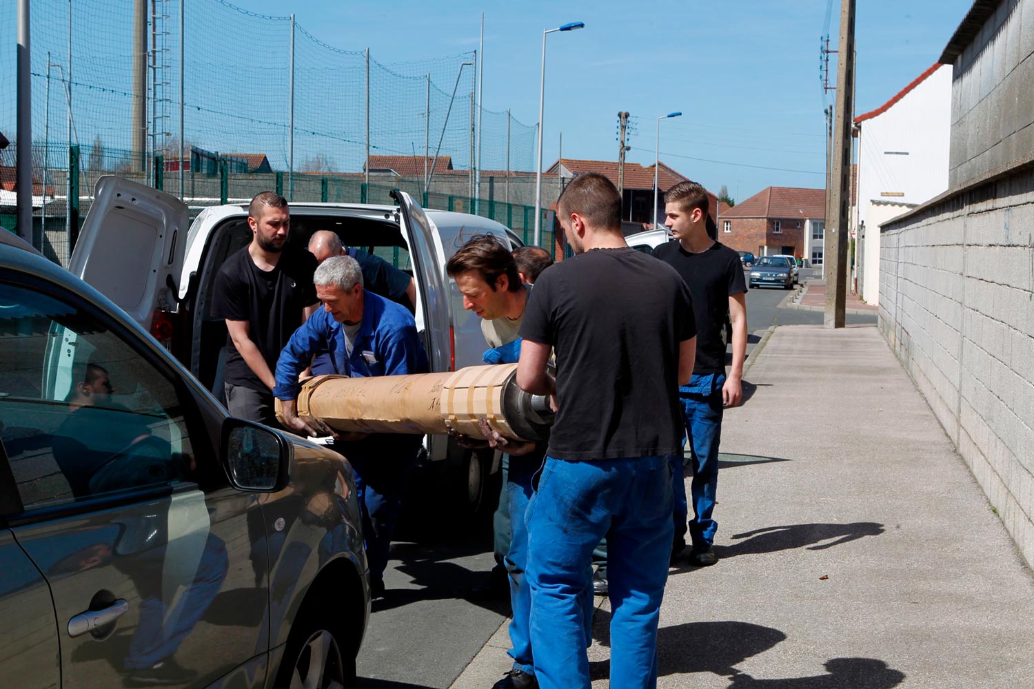 Der junge Arbeiter Matthieu trägt mit anderen Arbeitern eine große Textilspule (Chaine) in die Textilfirma Codentel  Fotografie von Heiko Schäfer