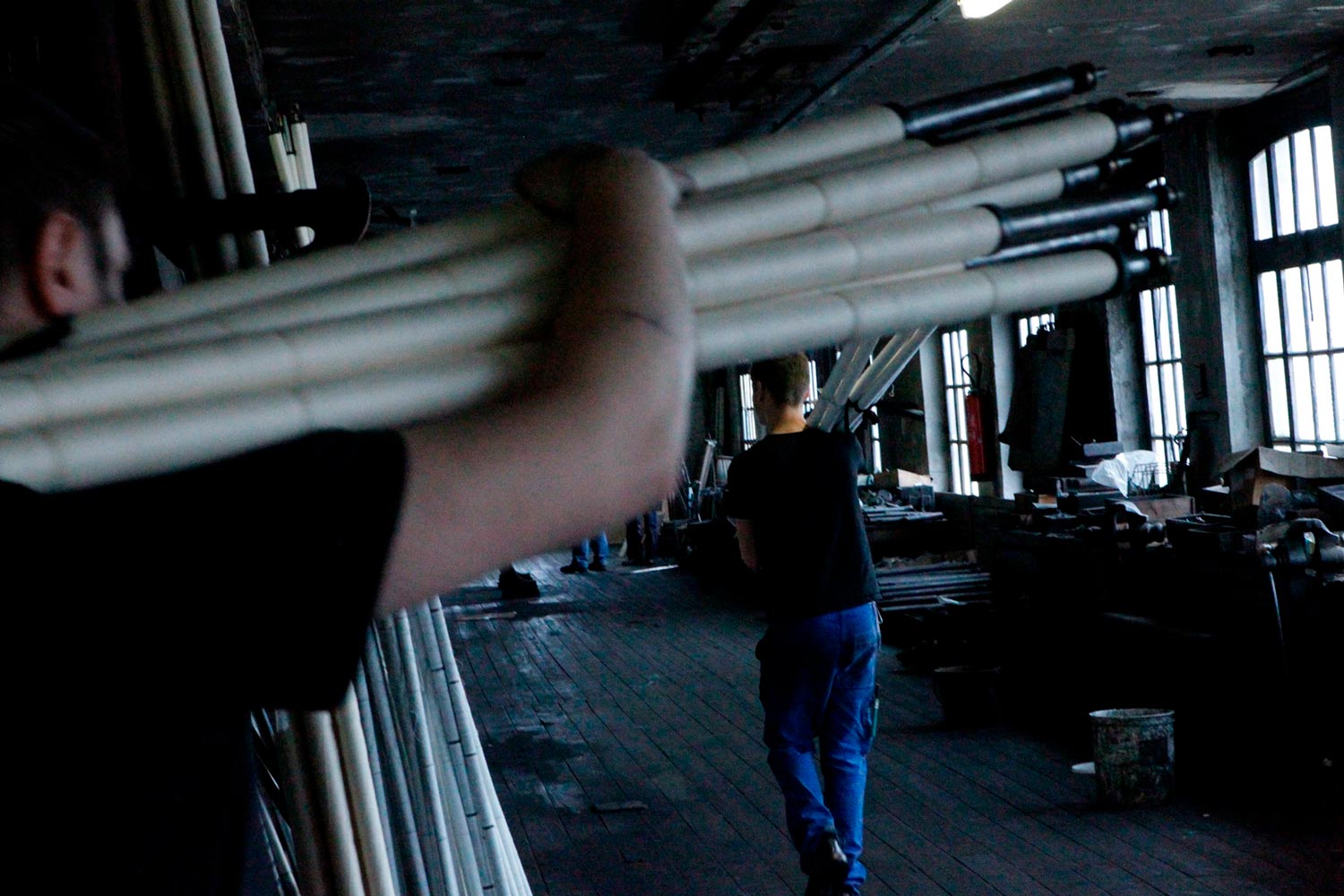 Der junge Textilarbeiter Matthieu trägt Textilspulen in der Textilfirma Codentel  Fotografie von Heiko Schäfer