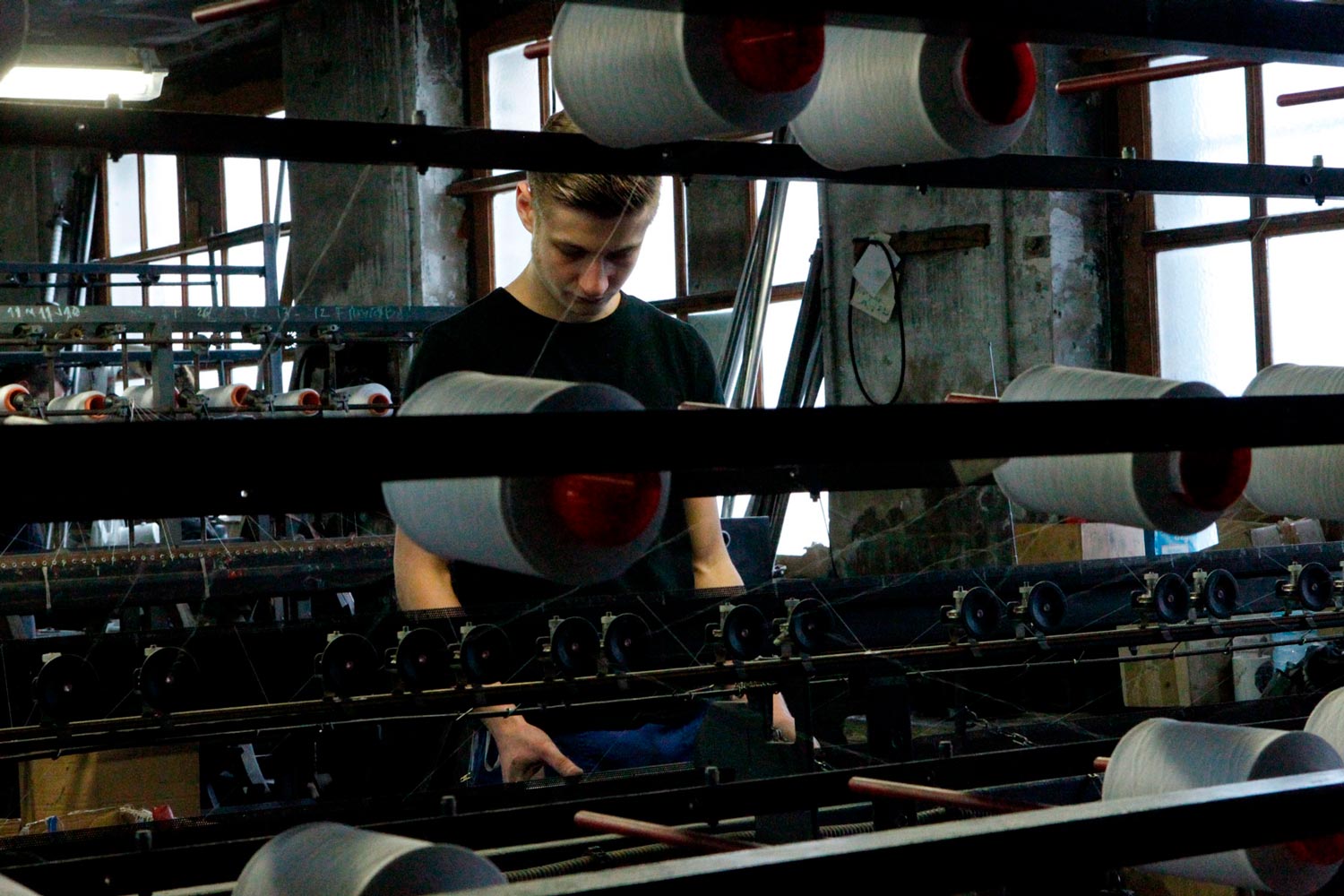 Der junge Arbeiter Matthieu arbeitet an einer Maschine in der Textilfirma Codentel  Fotografie von Heiko Schäfer