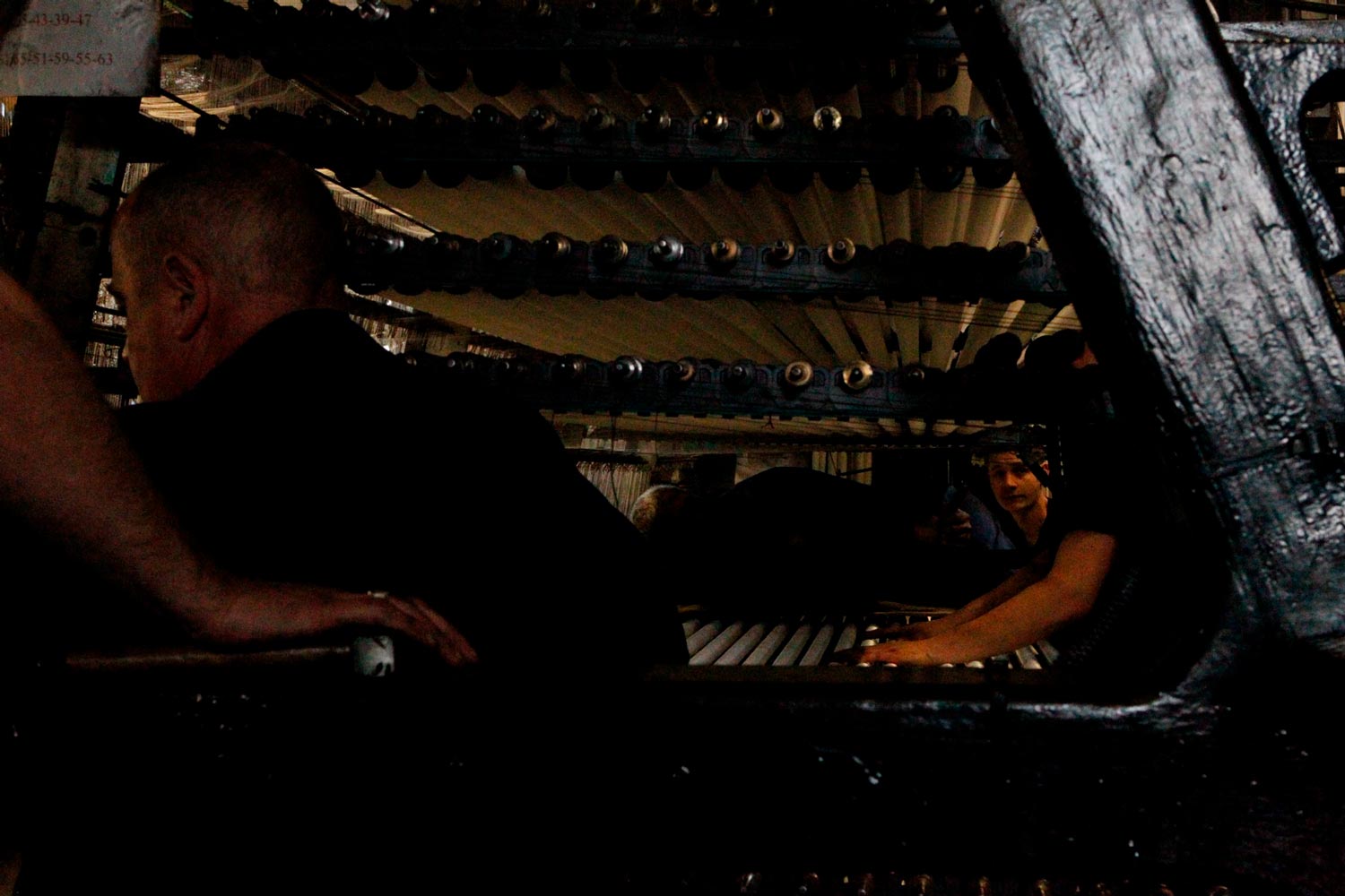 Der junge Arbeiter Matthieu trägt mit anderen Arbeitern eine große Textilspule (Chaine) in die Textilfirma Codentel  Fotografie von Heiko Schäfer