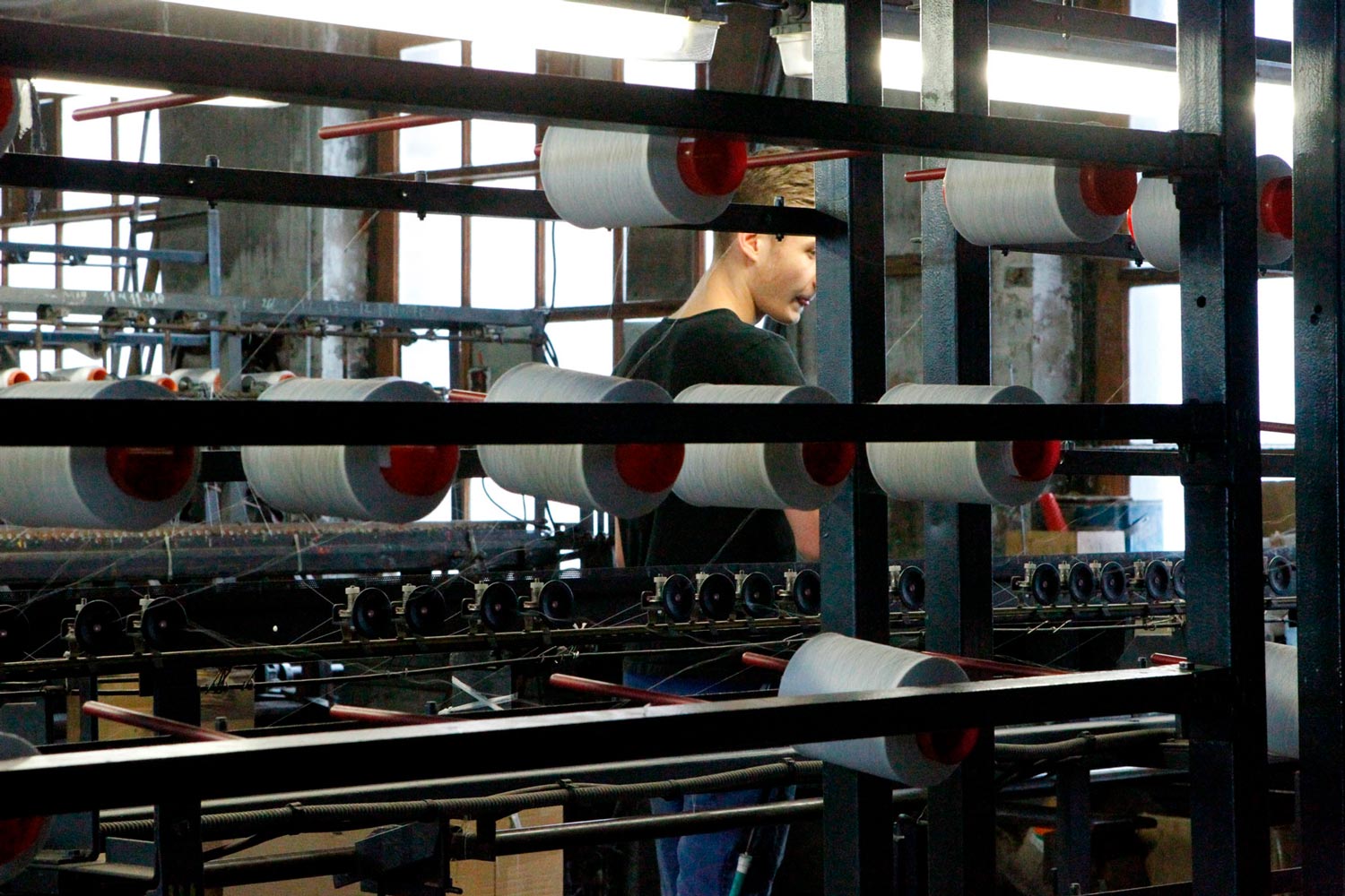 Der junge Arbeiter Matthieu arbeitet an einer Maschine in der Textilfirma Codentel  Fotografie von Heiko Schäfer