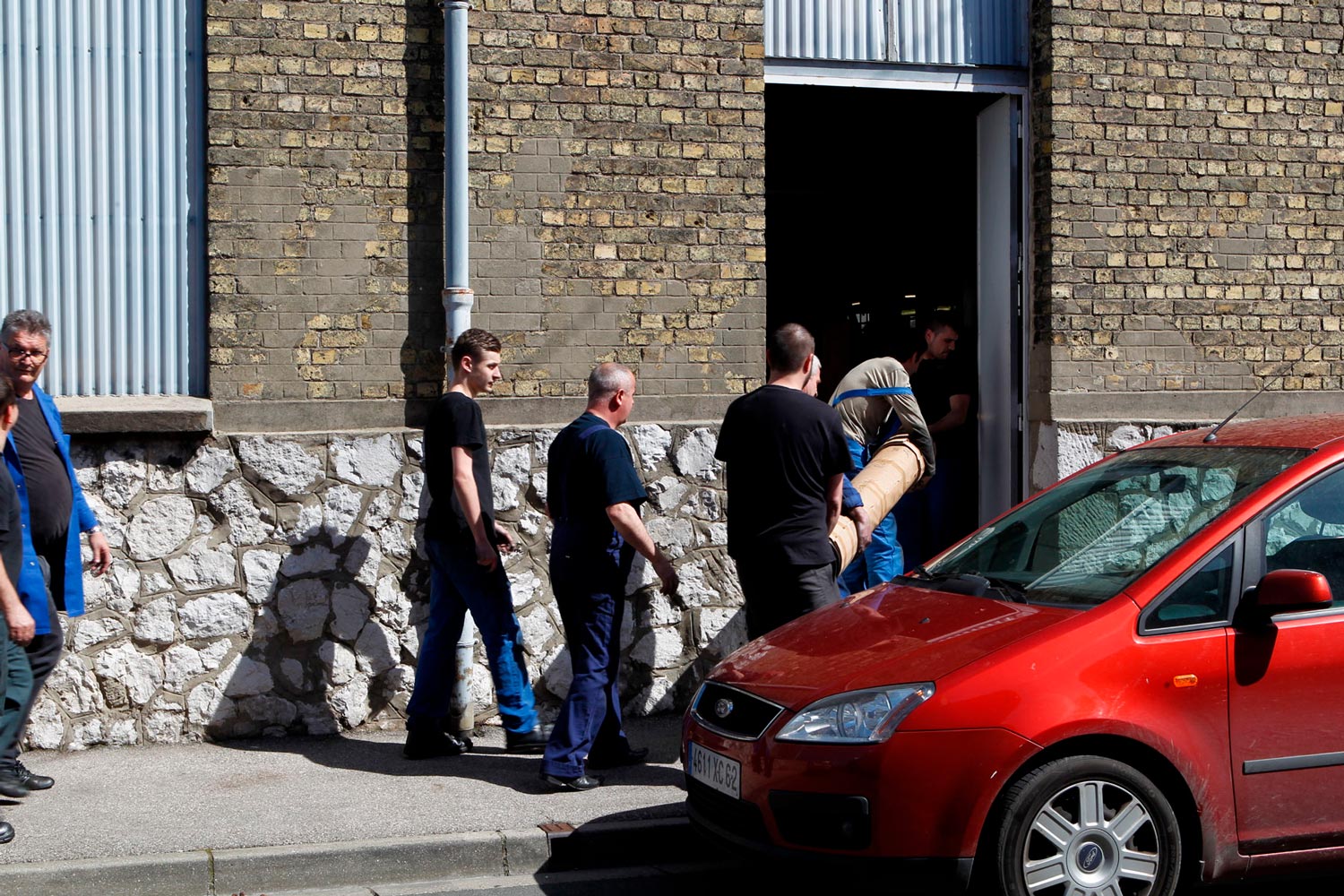 Der junge Arbeiter Matthieu trägt mit anderen Arbeitern eine große Textilspule (Chaine) in die Textilfirma Codentel  Fotografie von Heiko Schäfer