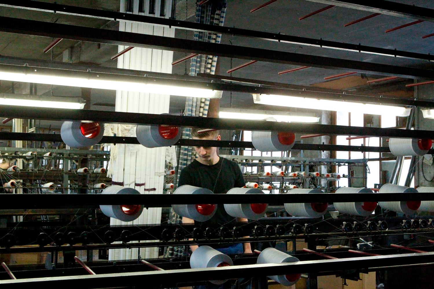 Der junge Arbeiter Matthieu arbeitet an einer Maschine in der Textilfirma Codentel  Fotografie von Heiko Schäfer