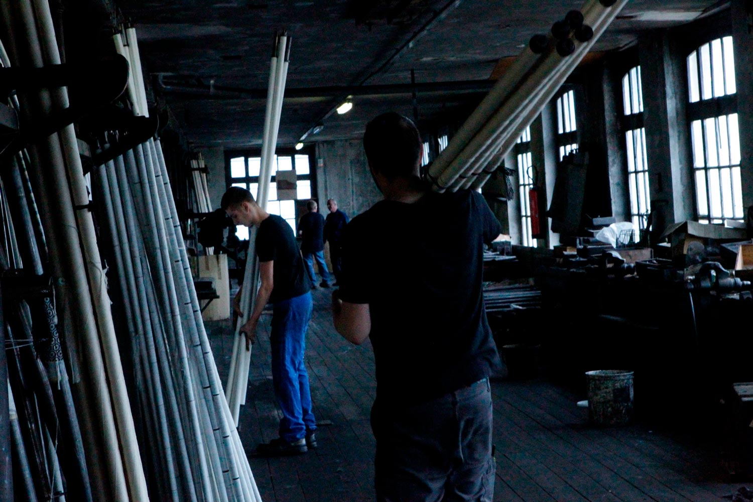 Der junge Textilarbeiter Matthieu trägt Textilspulen in der Textilfirma Codentel  Fotografie von Heiko Schäfer