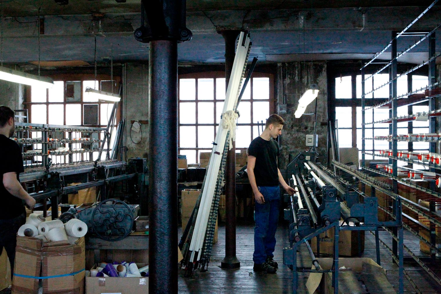 Der junge Arbeiter Matthieu steht an einer Maschine in der Textilfirma Codentel  Fotografie von Heiko Schäfer